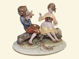 two figurines of children sitting on a rock