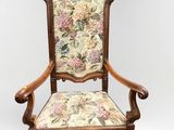 an old wooden chair with floral upholstered seat and arms