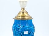an image of a blue glass lamp with a gold base and a light bulb on top of it