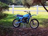 a blue dirt bike parked on the side of a stone wall