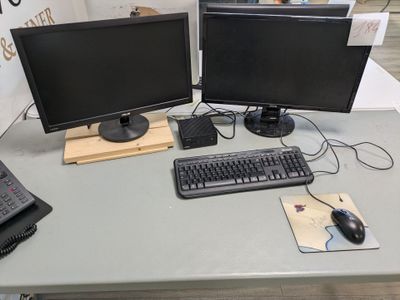 two computer monitors and a keyboard on a table