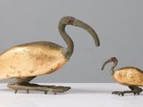 pair of bronze birds on stand on white surface with grey background