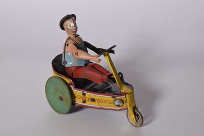 figurine représentant un homme sur un tricycle, posée sur une surface blanche