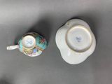 pair of porcelain cups and saucers with floral designs on them