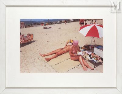 une photo d'une femme allongée sur la plage avec un parasol rouge et blanc