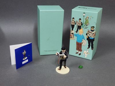 une figurine représentant un homme debout à côté d'une boîte remplie de livres
