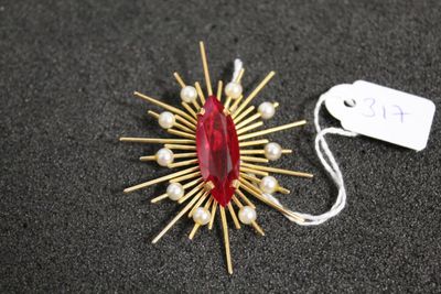 un gros plan sur une broche rouge ornée de perles, avec une étiquette de prix