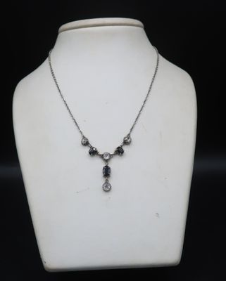 un gros plan d'un collier porté par un mannequin sur fond noir