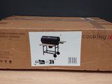 une boîte en carton posée sur une table sur laquelle se trouve un barbecue noir