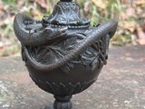 une statue représentant un serpent enroulé autour d'un vase