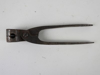une vieille paire de pinces posée sur une surface blanche