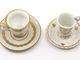 two cups and saucers sitting on a white table