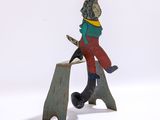 une figurine représentant un homme assis sur un morceau de bois