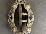 an antique silver buckle on a gray surface with a metal handle