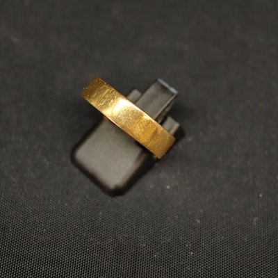 gros plan d'une bague en or sur une surface noire