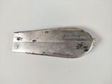 une cuillère en argent avec un manche en métal posée sur une surface blanche