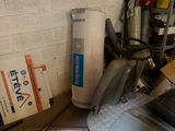 a washing machine in the corner of a room with a lot of clutter on the floor