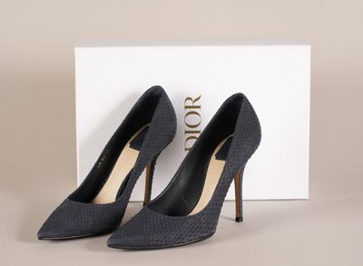 une paire de chaussures noires à talons hauts posée devant une boîte blanche