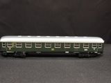 the green and white train car is sitting on a black surface