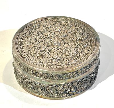 un coffret en argent richement décoré posé sur une surface blanche