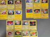 Plusieurs cartes Pokémon sont disposées sur une table devant un mur.