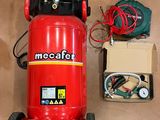 a red air compressor sitting on the floor next to a box of wires