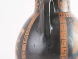 a black and orange vase sitting on a white surface