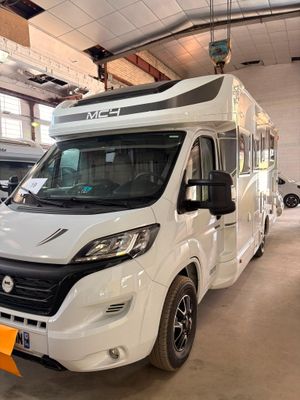 un camping-car blanc garé dans un garage avec d'autres véhicules