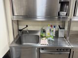 a stainless steel kitchen with a sink and a trash can