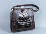 sac à main en cuir d'alligator marron avec une bandoulière en cuir sur fond gris