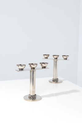 a set of five silver candlesticks on a white table