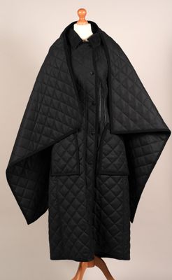 un manteau noir sur un mannequin sur fond blanc