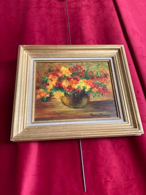 une peinture à l'huile représentant des fleurs dans un vase posé sur un tissu rouge