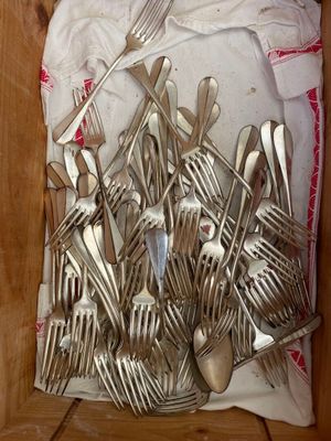many forks and spoons in a box on the floor