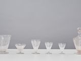 six glasses and a decanter sitting on a table