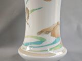 a white vase with flowers painted on it on a table