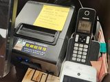 a cell phone sitting next to a printer and a cell phone on a desk