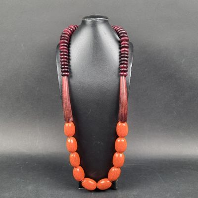 un collier composé de perles orange sur un mannequin noir