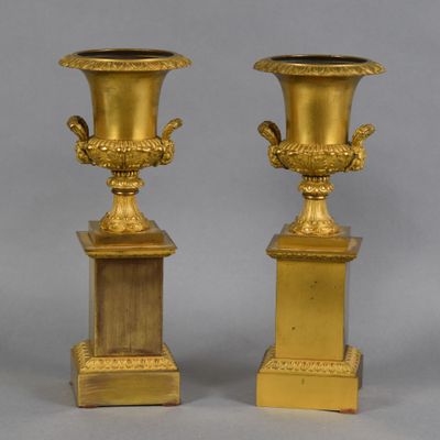 une paire de vases anciens en laiton sur socles, sur fond gris