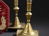 deux bougeoirs en or et une boîte rouge sur laquelle figure une image de Jésus