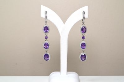 Boucles d'oreilles en améthorate violet et topazte blanc, présentées sur un socle blanc