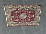 a red and white rug sitting on top of a cement floor