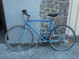 un vélo bleu appuyé contre un mur de pierre