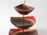 three tiered serving tray with a gold handle and a red and black design