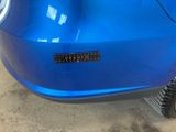 the rear end of a blue car with a sticker on it ' s bumper