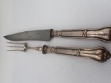 two knives and a fork on a white surface