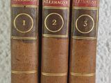 three old books are lined up on a shelf next to a wall
