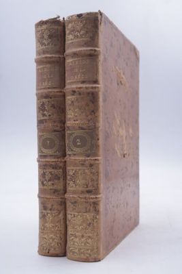 deux vieux livres posés l'un sur l'autre sur une surface blanche