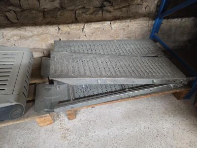 une grille métallique posée sur une palette, à côté d'une caisse métallique