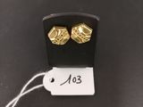 a close up of a pair of gold earrings on a black surface